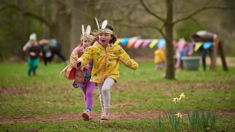 Children wearing colourful raincoats run through the Felbrigg estate on an Easter trail, with daffodils blooming.